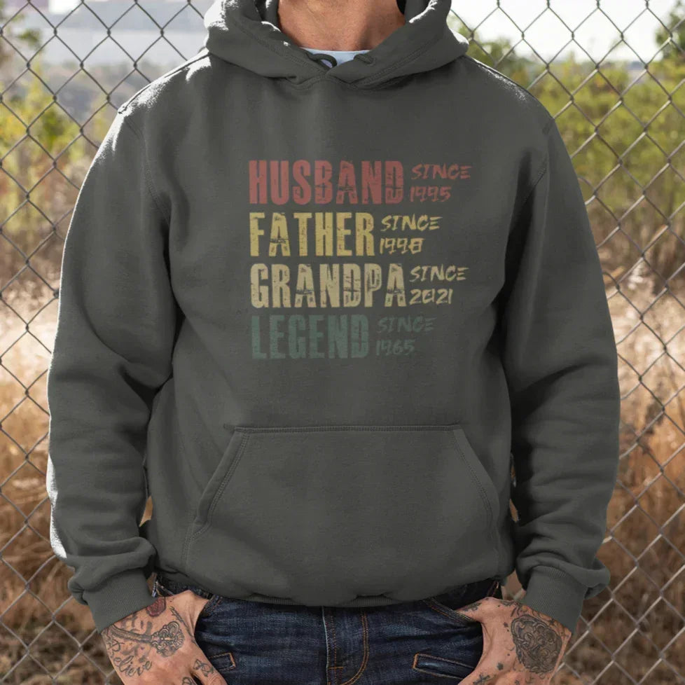 Pullover Hoodie mit Aufdruck Husband Father Grandpa Legend, getragen von tätowiertem Mann vor Zaun