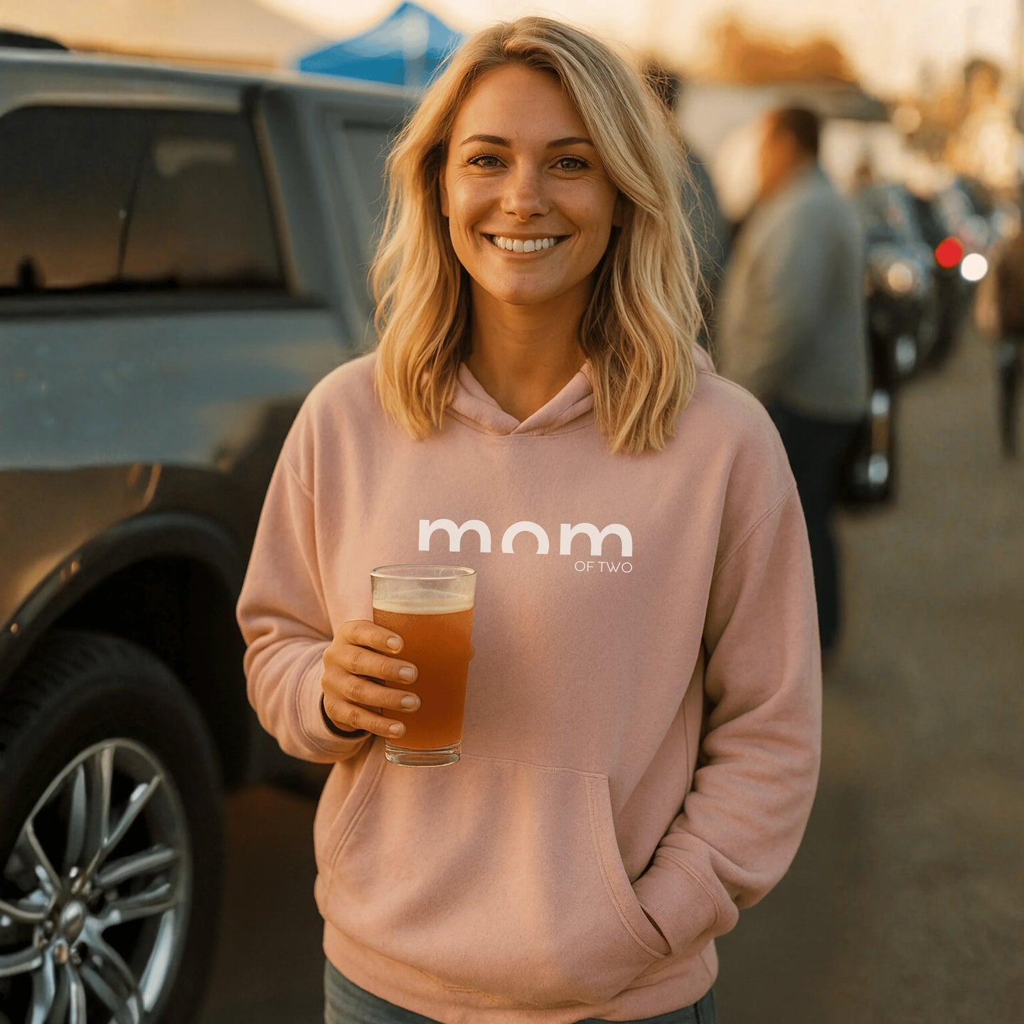MAMA Hoodie MOM OF TWO – rosa Hoodie, lächelnde Frau hält Getränk