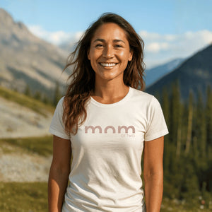 Frau im Freien trägt T-Shirt mit Aufdruck mom OF TWO vor Berglandschaft